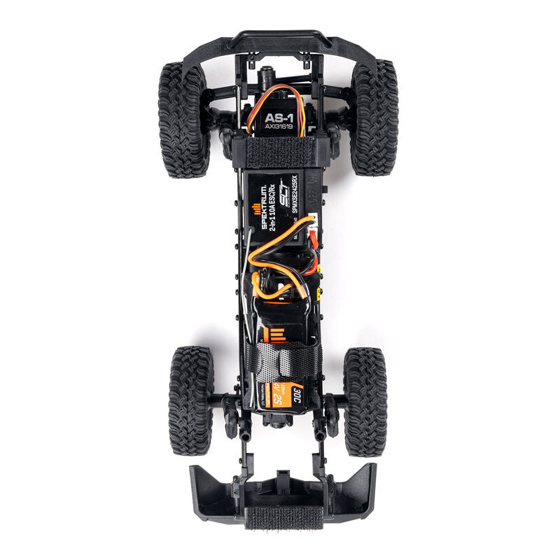 Axial 1/24 SCX24 Base Camp 4X4 RTR brushed rock crawler on rough terrain, showcasing detailed design and off-road features.