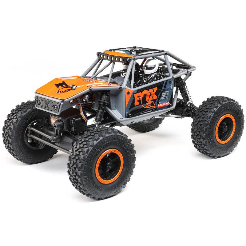 Gray and orange Axial 1/18 UTB18 Capra 4WD RTR trail buggy on rugged terrain, showcasing detailed off-road design.