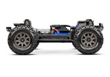 Traxxas Mini Maxx 1/16 scale RC truck chassis side view showing detailed black and silver components and rugged construction.