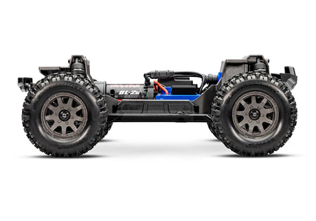 Traxxas Mini Maxx 1/16 scale RC truck chassis side view showing detailed black and silver components and rugged construction.