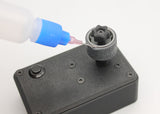 Reflex Racing RRE011 1:28 scale tire gluing machine for RC cars, shown in a close-up image with tools and parts.