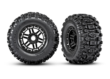 Pair of Traxxas Maxx 2.8-inch black wheels with Sledgehammer tires, showing the rugged off-road tread pattern and sturdy design.