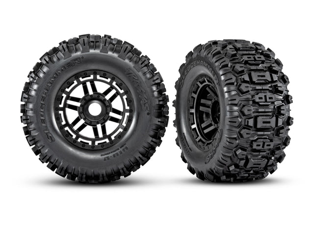 Pair of Traxxas Maxx 2.8-inch black wheels with Sledgehammer tires, showing the rugged off-road tread pattern and sturdy design.