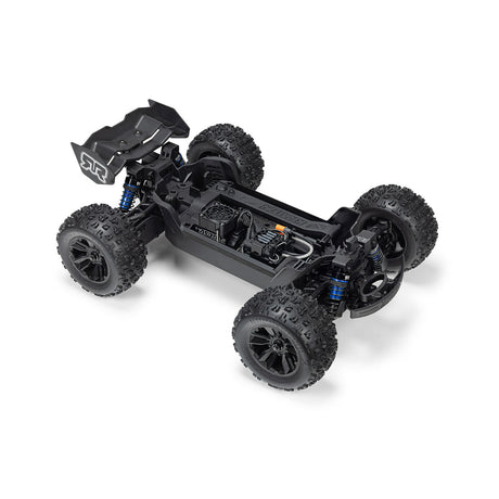 ARRMA 1/16 Mini Kraton 3S RC truck with charger and battery, showcasing the detailed miniature off-road vehicle on a display surface.