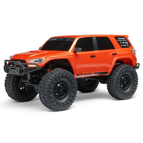 Axial 1/24 SCX24 Toyota 4Runner 4x4 RTR brushed rock crawler on rugged terrain with detailed exterior features.