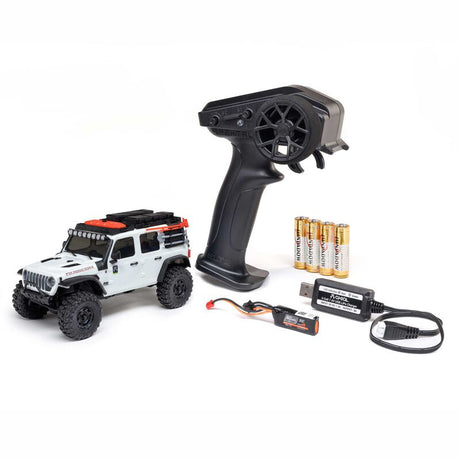 Axial 1/30 scale SCX30 Jeep Wrangler JLU 4x4 RC rock crawler on rough terrain with detailed exterior and rugged tires.