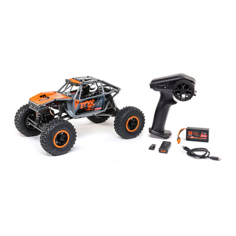 Gray and orange Axial 1/18 UTB18 Capra 4WD RTR trail buggy on rugged terrain.