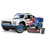 ARRMA Mojave GROM 223S DSC 4x4 RTR brushless desert truck shown in off-road terrain with rugged tires and desert camouflage.