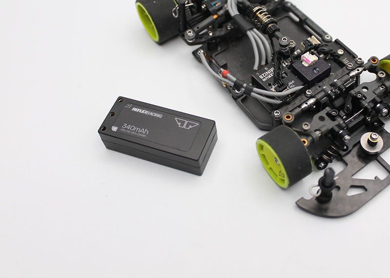 Reflex Racing RRE012 340mAh 7.6V LiHV hardcase RC car lipo battery lying on a surface with cables and tools nearby.