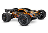 Orange Traxxas XRT 8S remote control monster truck on rugged terrain, showcasing its large tires and durable design.