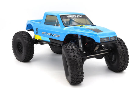 Vanquish VRD Stance 4x4 RTR crawler with blue wheels and wide stance, front view showing detailed suspension and rugged tires.