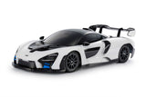 Tamiya TT-02 McLaren Senna model kit showing detailed plastic car body and assembly parts on a work surface.