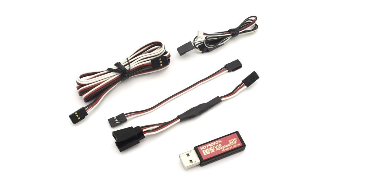 Kyosho I.C.S USB Adaptor HS 82083 connected to a compressor, showing a compact, black electronic adapter with USB port for RC tools.